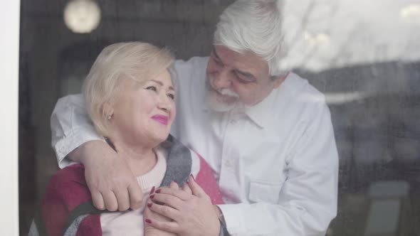 Elderly Caucasian Man Covering His Thoughtful Charming Wife with Blanket. Portrait of Aged Married