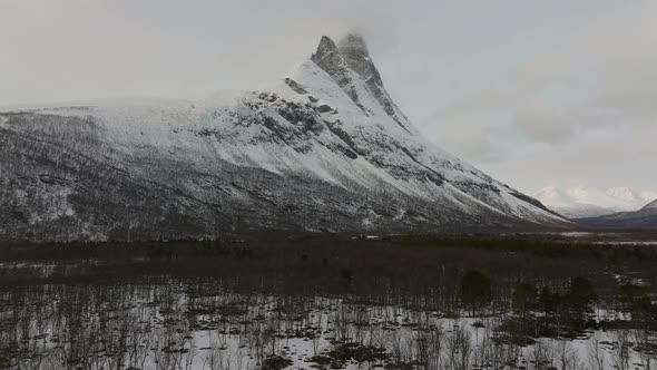 Flying over the forest towards the snow covered Otertinden mountain in northern Norway. 4k drone sh