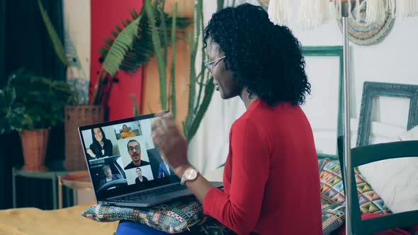 Young African Lady Is Using a Laptop for a Videocall with Lots of People