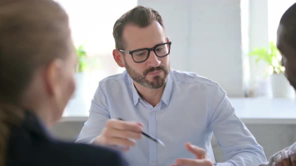 Serious Businessman Talking to Colleagues in Office