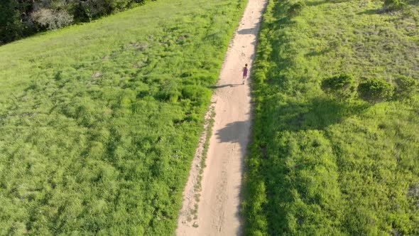 Aerial of Young Woman Running on a Forest Trail at Sunset