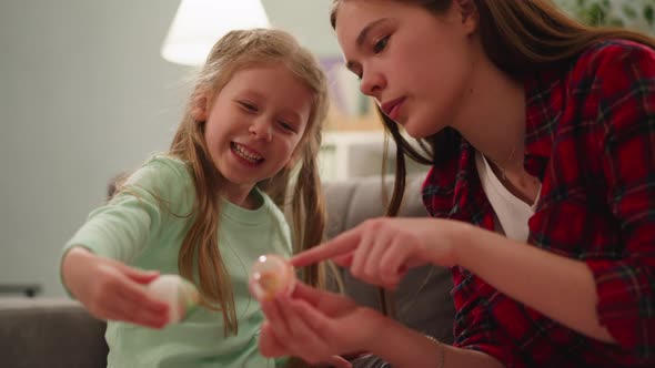 Teenage Girl and Little Sister Compare Vivid Easter Eggs