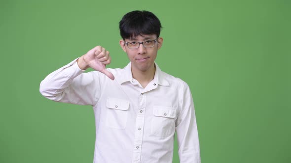 Young Asian Businessman Nodding Head No and Giving Thumbs Down