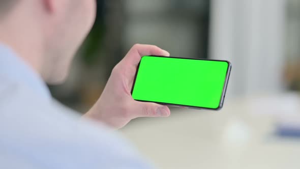 Rear View of Young Man Looking at Smartphone with Chroma Screen