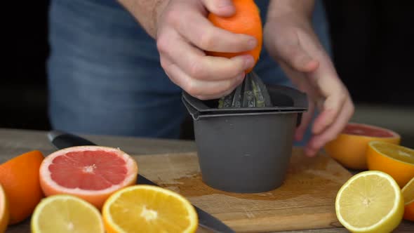 A Man is Squeezes Orange Juice with Citrus Juicer