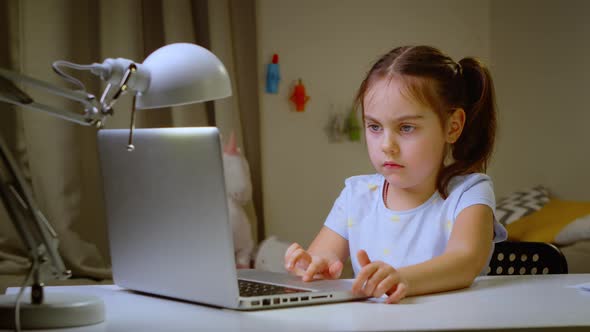 Little Girl Studying at an Online School on a Laptop