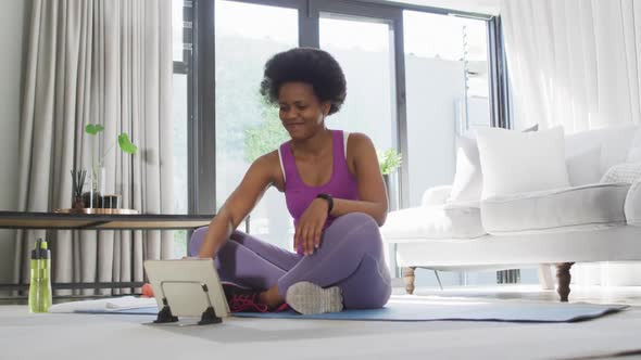 Happy african american wearing sportswear, exercising, using tablet