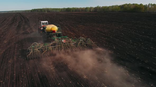 Agriculture Tractor Sowing Seeds and Cultivating Field in Late Afternoon. Agricultural Tillage