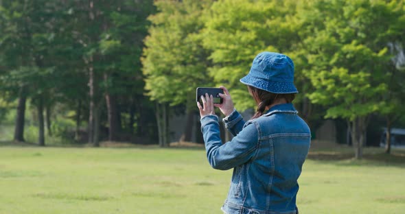 Woman use of mobile phone to take photo in countryside