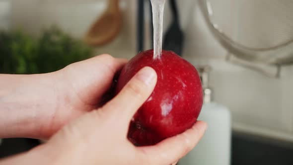 Female Hands Washing Apple Under Water in Sink