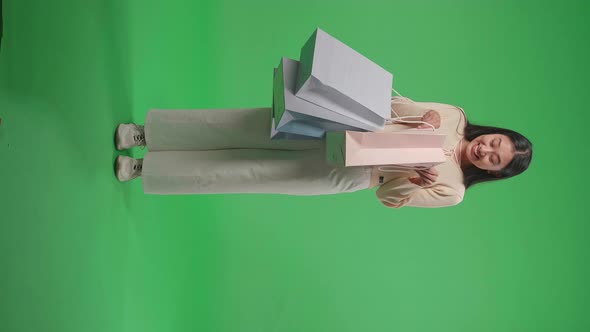 Full View Of Woman Being Happy After Opening Shopping Bag While Standing In Front Of Green Screen