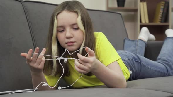Teenage Girl Untangle Wires From Wired Headphones