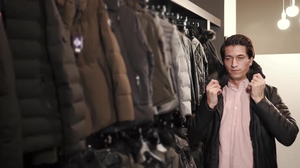 a Young Man Chooses a Jacket in a Clothing Store He Tries on a Sample for Himself