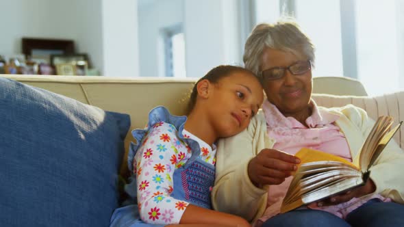 Grandmother and daughter reading book in living room