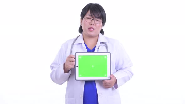 Happy Overweight Asian Woman Doctor Talking While Showing Digital Tablet