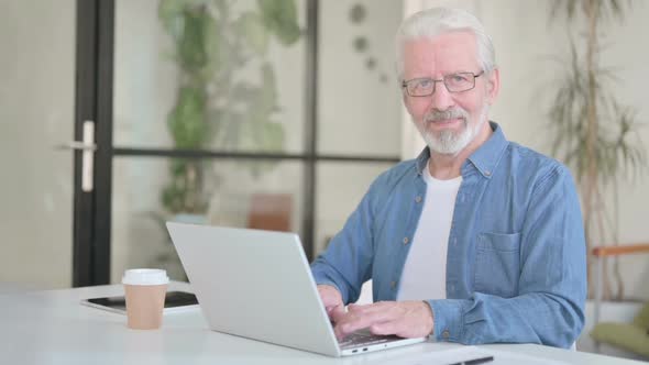 Senior Old Man Showing Yes Gesture By Head Shake While Using Laptop