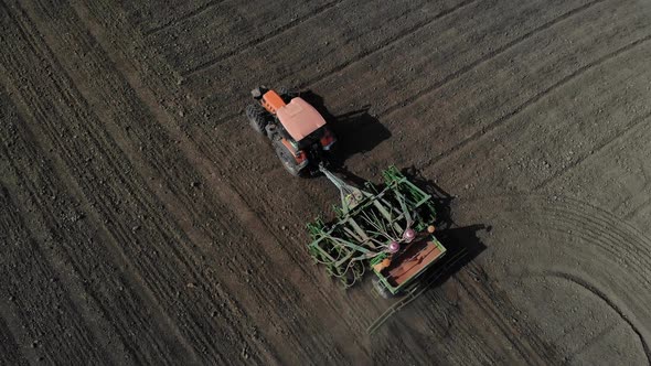 Orange Tractor Plows the Field. Aerial View. 