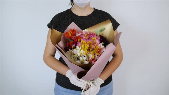 Woman in the Hand Gloves and Mask Holding Colorful Flowers Bouquet of Alstroemeria on White