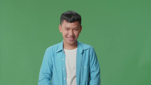 Smiling Young Asian Boy Positively Shaking His Head At The Camera In The Green Screen Studio
