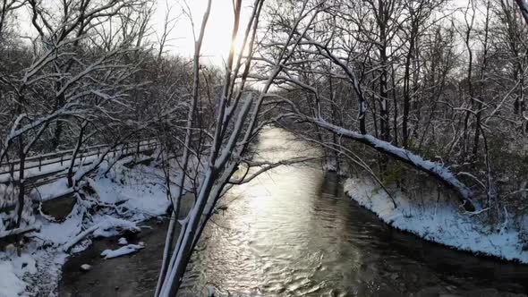 Rising aerial shot over wintry creek and forest in Michigan, USA