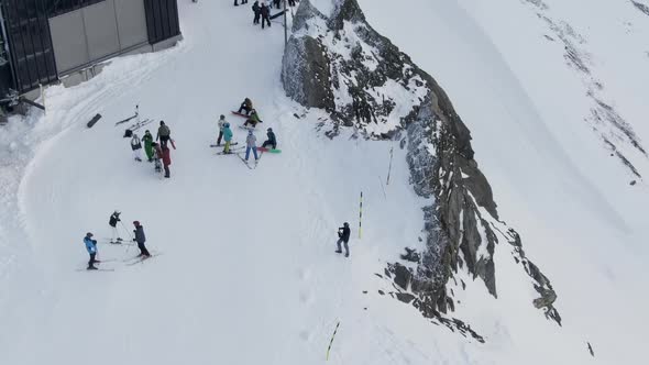 People on Snowy Ski Resort, Drone View of Crowd of People Walking Near Shed on Snowy Mountain Ridge