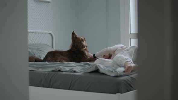 Girl and her pet friend cuddles on bed