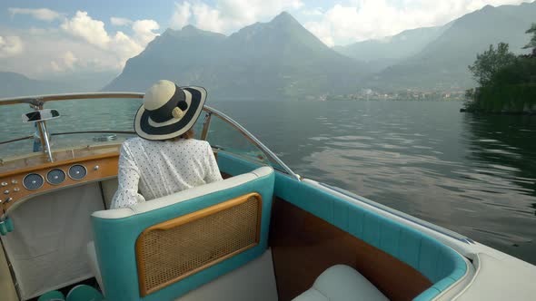 A woman on a classic luxury wooden runabout boat on an Italian lake.