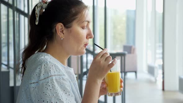Attractive Young Lady Drinks Juice in Cafe