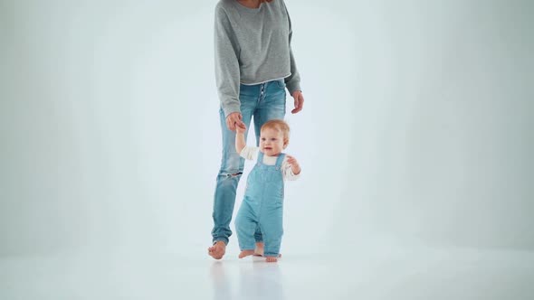 Mom holds the baby by the hand and teaches to walk. studio slow motion