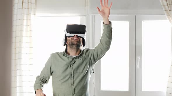 Young man exploring cyberspace in VR goggles at home