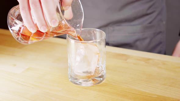 Pouring a negroni from a mixing glass