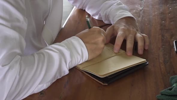 Groom's vow. Male hands write love letter in notebook to bride on the wedding. Bow-tie, mobile phone