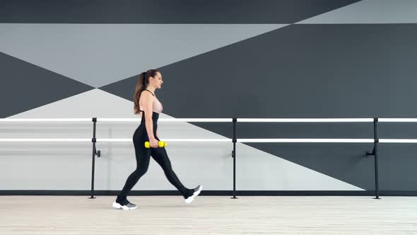 Fitnesswoman Practicing Lunges Using Dumbbells