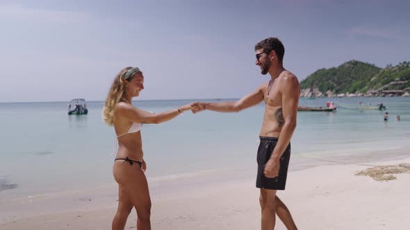 A Side View of a Young Romantic Couple Shaking Hand and Kissing on the Beach