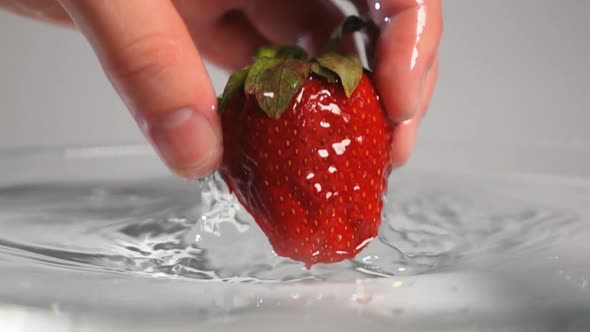 Hand Dropping Out Strawberry Into Water