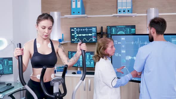 Female Doctor in Sport Science Checking the Energy of Female Athlete on Tv Monitor