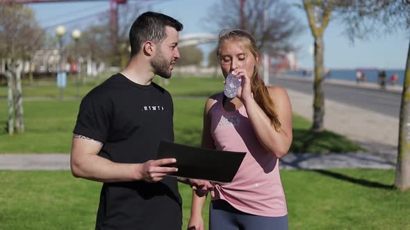 Thoughtful Young Woman Looking at Training Plan with Coach