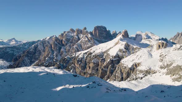 Idyllic harsh snowy alps valley landscape elevated aerial view rising above sunlit mountain terrain