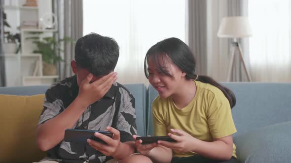 Children Playing Video Games On Mobile Phone At Home, Girl Celebrating Victory And Boy Disappointed