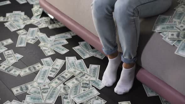 Rich Asian woman sitting on couch and counting money, female billionaire