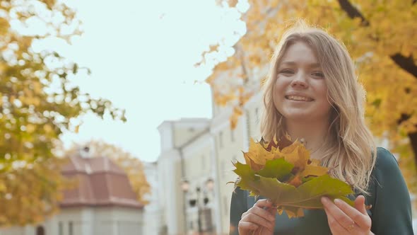 Young Charming Girl in Dress is Enjoying Autumn in the Park