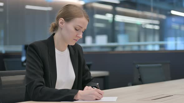 Beautiful Businesswoman Writing on Paper in Office