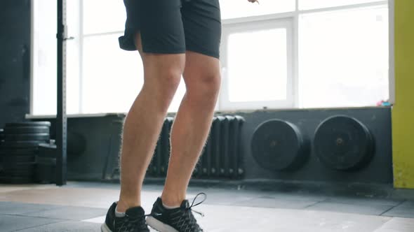 Tilt-up of Sporty Man Jumping with Skipping Rope in Gym Working Out Alone
