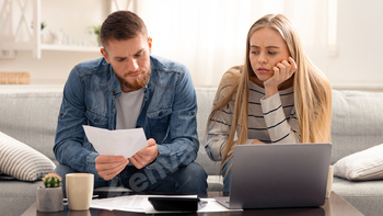 Unhappy couple reading bank notification, calculating budget