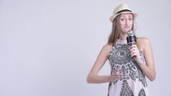 Happy Blonde Tourist Woman Using Microphone and Presenting Something