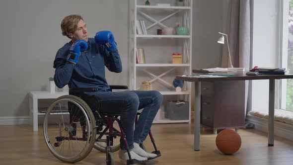 Young Sportsman in Wheelchair Putting on Boxing Gloves Fighting Shadow in Slow Motion