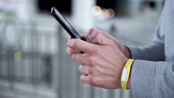 Modern sports man using a smartphone outdoors. Close-up shot