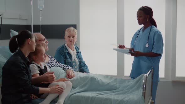 African American Assistant Explaining Medication to Old Man and Visitors