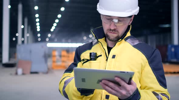 Engineer In Helmets With Tablet Device And Big Paper Drawings Discussing