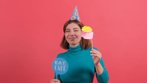 Happy Young Woman in Party Hat Holding Birthday Accessories on Red Background.